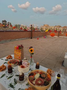 a table topped with lots of food next to a brick wall covered in flowers and vases