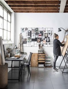 a woman standing in front of a easel with pictures on the wall