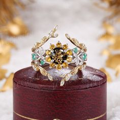 a fancy ring is sitting on top of a red box with gold and green accents