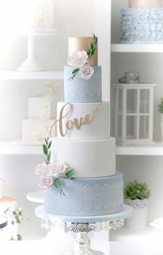 a three tiered wedding cake with flowers on top and the word love painted on it