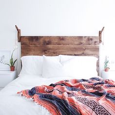 a bed with a blanket on top of it next to a potted house plant