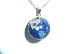 This beautiful pendant features a ball or sphere shape depicting the world globe, and it's continents. The globe is a deep cobalt blue lapis lazuli.  The continents are inlaid Mother of Pearl, Jasper, Jade and Turquoise.  Each continent's name is labeled.  There are tiny gold leaf longitude and latitude lines. This pendant / charm is in excellent vintage condition. It has a beautiful sheen, and deep rich color (as seen in photo #2). Globe measures 3/4 inch. 1 inch hanging length including the bail. I have added a 24 inch 14K gold plated chain. NOTE: Although the pendant is vintage, the chain is not. This pendant has a beautiful luster that is best seen in photo #2 taken without flash. Blue Engraved Jewelry For Keepsake, Blue Engraved Necklace For Keepsake, Blue Round Keepsake Jewelry, Lapis Lazuli Pendant, World Globe, Rose Pendant, Globe Pendant, Blue Lapis, Gold Plated Chains