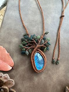 a necklace with a blue stone hanging from it's center, surrounded by other jewelry items