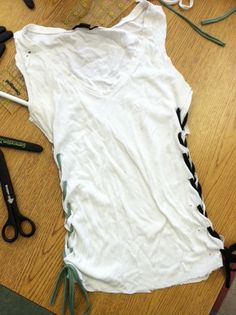 a white shirt sitting on top of a wooden table next to scissors and other items