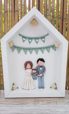 a wedding cake topper with a bride and groom in a small white house frame