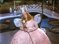 a woman in a pink ball gown holding a wand and wearing a tiara with stars on it