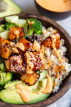 a wooden bowl filled with rice, broccoli and chicken on top of it