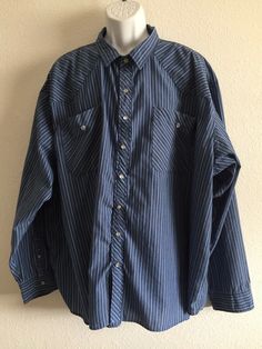 This great looking western shirt has been altered by sewing a seam on one side of snaps.  This keeps shirt closed and makes it a pull over. The top button and snap are original so can be opened and closed making this shirt a pull over. This shirt was also missing the size tag.  All measurements point to XXL.  The shirt still looks like new.   One photo looks grey, but the shirt is actually a nice bright blue.  65% polyester and 35% cotton for easy care, wash and dry.   Please review measurements Western Long Sleeve Shirt With Buttons, Western Style Long Sleeve Shirt With Buttons, Long Sleeve Flannel Shirt With Button Closure, Long Sleeve Cotton Shirt With Snap Buttons, Western Long Sleeve Top With Button Closure, Western Long Sleeve Shirt With Button Closure, Western Style Relaxed Fit Long Sleeve Tops, Western Long Sleeve Tops With Snap Buttons, Western Style Long Sleeve Relaxed Fit Tops