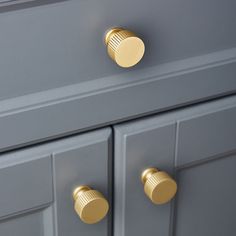 two gold knobs on a gray cabinet