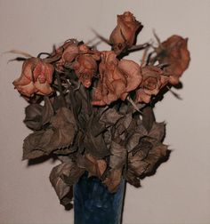 a blue vase filled with dried flowers on top of a table