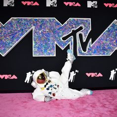 an astronaut is laying on the pink carpet with his arms in the air and feet up