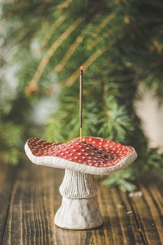 a red and white polka dot covered cake on a table with pine branches in the background