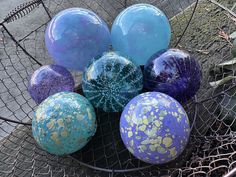 there are many different colored balls in the basket on the ground, and one is blue with gold spots