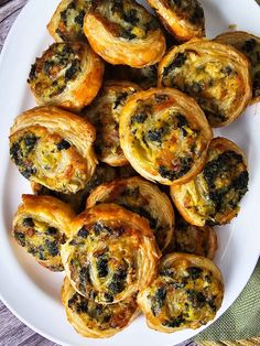 a white plate topped with mini pastries covered in cheese and spinach toppings