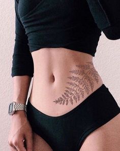 a woman with tattoos on her stomach holding a cell phone