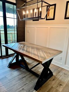 a wooden table sitting in the middle of a room with pictures on the wall behind it