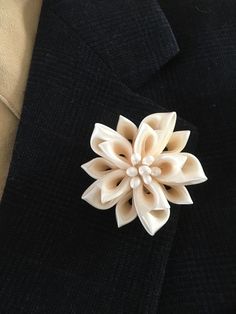 a black jacket with a white flower brooch on it's lapel pin