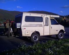 a white truck parked on the side of a road with people standing around in front of it