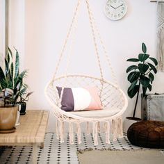 a hammock chair hanging from the ceiling in a room with potted plants