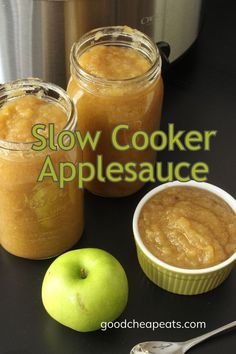 jars of homemade applesauce next to an apple, a spoon, and a slow cooker. Crock Pot Applesauce Recipe, Crockpot Strawberry Applesauce, Diy Applesauce, Crock Pot Applesauce, Apple Sauce Recipes Crockpot, Chunky Applesauce Recipe Crock Pots, Crockpot Applesauce Easy, Crock Pot Applesauce For Canning, Homemade Applesauce Crockpot