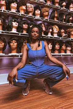 a woman kneeling down in front of a display of mannequin heads