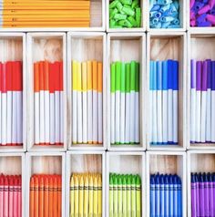 many different colored crayons are lined up in boxes