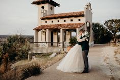 a bride and groom standing in front of a large building on the side of a road