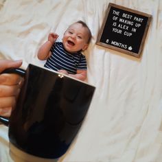 a baby is sitting in a coffee cup and being held by someone's hand