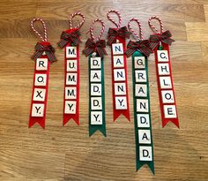 four christmas ribbon name tags with candy canes in them on a wooden floor next to each other