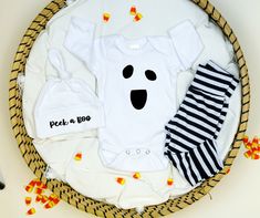 a baby's first halloween outfit with candy corn on the floor next to it