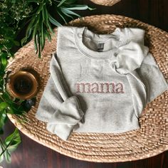 "Time to get comfy! This cozy sweatshirt is embroidered with the word \"mama\" in a beautiful floral font. The sweatshirt is the classic cozy sweatshirt of your dreams! Pick your favorite thread color (and even match your baby!) -Sweatshirt brand: Gildan -Color: light grey -Sizes available: Adult Small - Adult 2XL (3XL available for select options upon request)  -Fit: True to size with a slightly roomy fit. Size up for a true oversize fit -Machine embroidered" Embroidered Text Sweatshirt For Loungewear, Loungewear Sweatshirt With Embroidered Text, Fall Sweatshirt With Embroidered Logo For Loungewear, Cozy Sweatshirt With Letter Embroidery For Fall, Cozy Letter Embroidery Sweatshirt For Fall, Cozy Fall Sweatshirt With Letter Embroidery, Fall Sweater With Embroidered Logo For Loungewear, Custom Embroidery Loungewear Tops, Custom Embroidered Relaxed Fit Tops For Loungewear