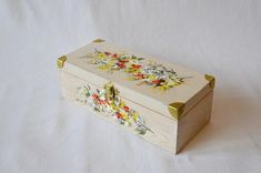 a small wooden box with flowers painted on the side and gold trimming around it