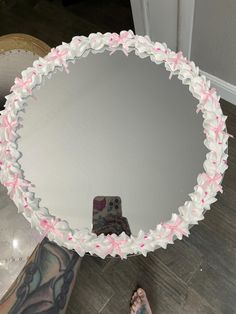 a person standing in front of a large mirror with pink bows on the bottom half