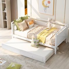 a white day bed sitting on top of a wooden floor next to a book shelf