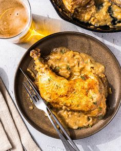 a plate with chicken and gravy next to a glass of beer