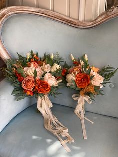 two bouquets of flowers are sitting on a blue chair with ribbon tied around them