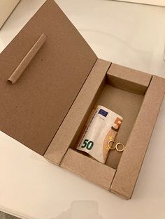 an open cardboard box with two wedding rings and a roll of toilet paper in it