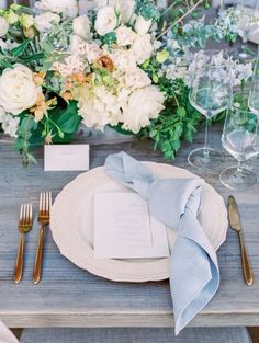 a place setting with silverware, napkins and flowers