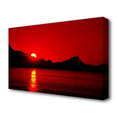 the sun is setting over water with mountains in the background canvas wall art print - red