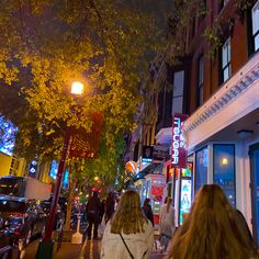 two women walking down the street at night in front of a building with neon lights