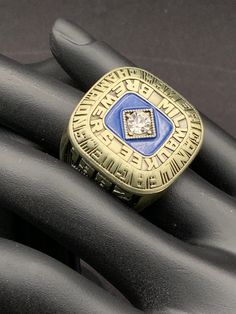 a gold and blue ring sitting on top of a black mannequin