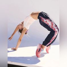 a woman doing a handstand on top of a white surface