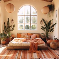 a bed sitting under a large window in a bedroom next to potted plants and cacti