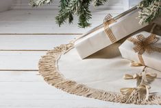 two wrapped presents sitting on top of a white rug next to a christmas tree branch