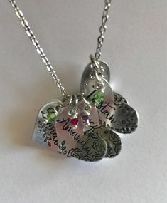 Family name hearts necklace. Add a heart with crystal birthstone for each loved one. Choose kids, pets, husband, wife, yaya, Mimi, grandmother, godmother, aunt. Leave names and birth months and also if you would like leaves or flowers stamped around the names in notes to seller at check out. Thank you. NOTE*----leaves and flower spacing on each heart will depend on the length and spacing of names. *Hand stamped items are artistically imperfect, unlike mass produced machine made jewelry. Letters Hand Stamped Silver Name Necklace For Mother's Day, Silver Hand Stamped Name Necklace For Mother's Day, Silver Hand Stamped Necklace For Mother's Day, Personalized Cute Charm Necklaces For Anniversary, Cute Personalized Charm Necklaces For Anniversary, Personalized Birthstone Necklace For Mother's Day Keepsake, Silver Birthstone Necklace For Mother's Day Keepsake, Personalized Heart Birthstone Necklace For Mom, Mother's Day Hand Stamped Heart Pendant Charm Necklace