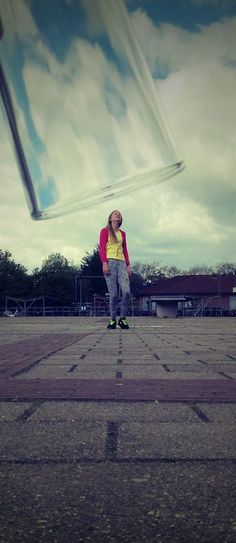 a person is flying a kite in the air with their legs spread out and there are clouds behind them