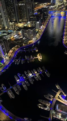 an aerial view of a city at night with lots of lights and boats in the water