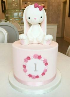 a pink cake with a white bunny sitting on it's top and the number 1