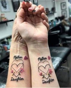 two girls with matching tattoos on their arms, one has a heart and the other has flowers