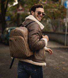 a man with a backpack and sunglasses walking down the street